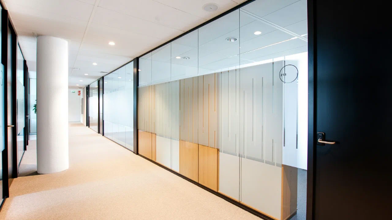 A glass-walled office corridor with a clock on the wall