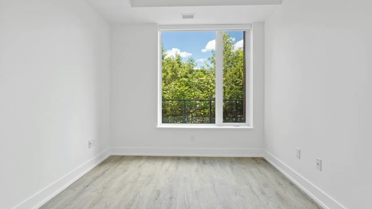 An empty room with bare floorboards and a tall window