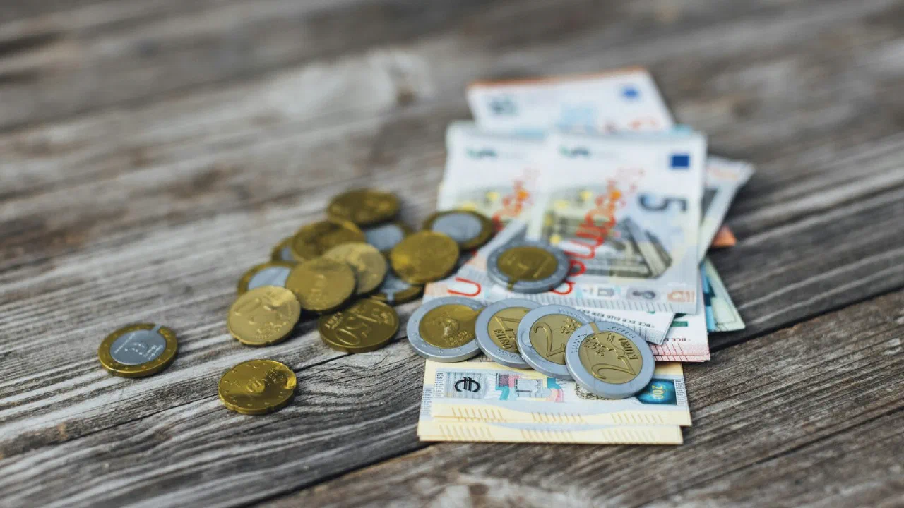 euro banknotes and coins piled on a wooden table