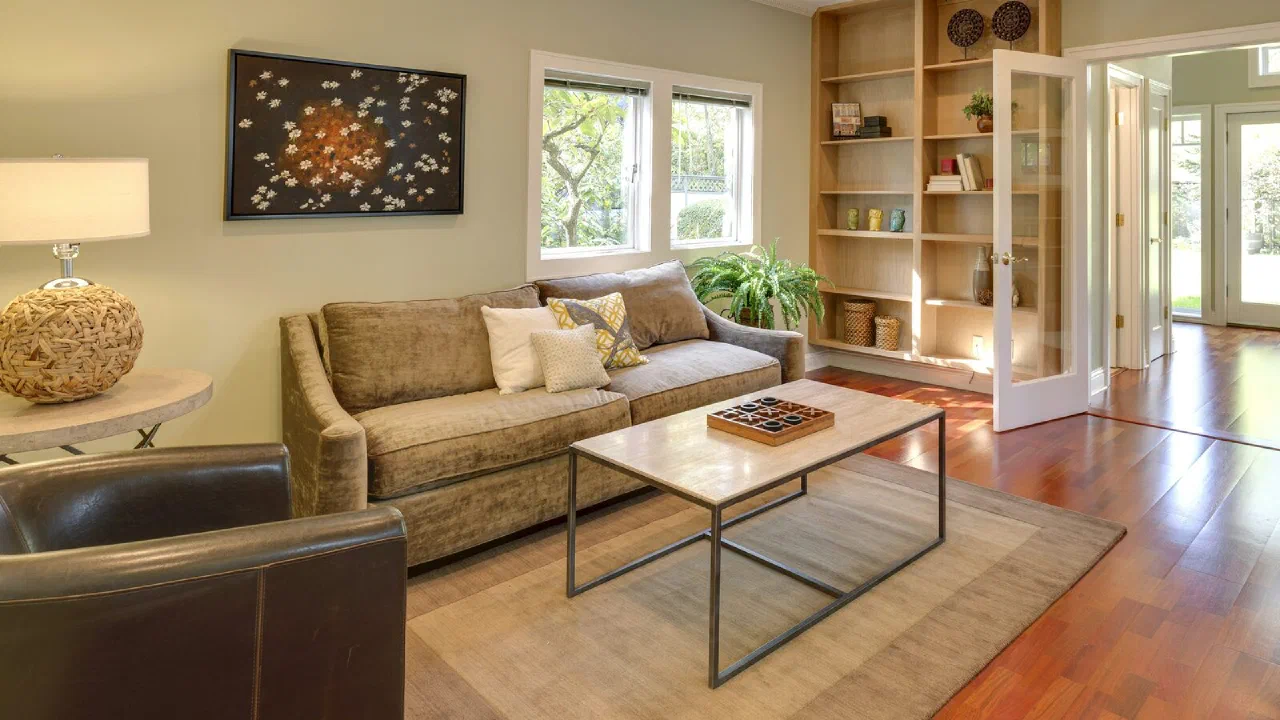 A small living room with a sofa, a wooden table and a bookshelf