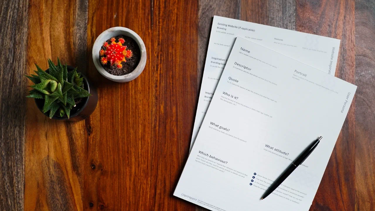 printed papers and a pen spread across a wooden table