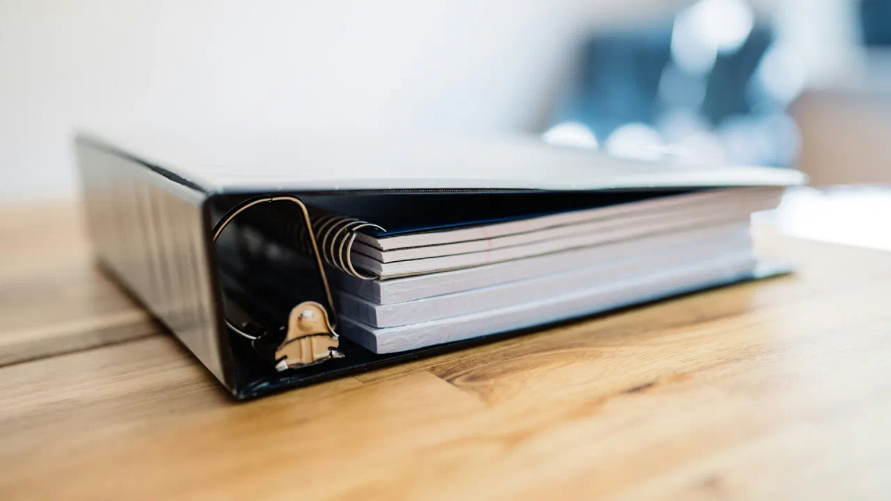 An open ring binder with loose pages inside, photographed close up