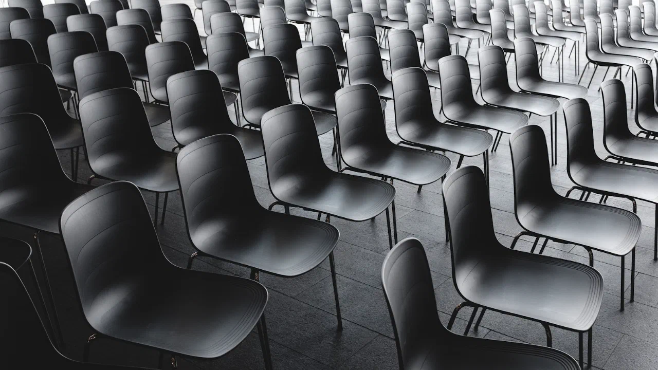 rows of empty black chairs in a waiting area