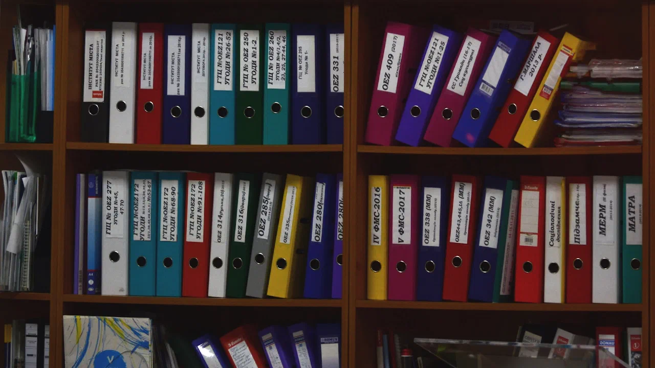 rows of ring binders lined up on wooden office shelves
